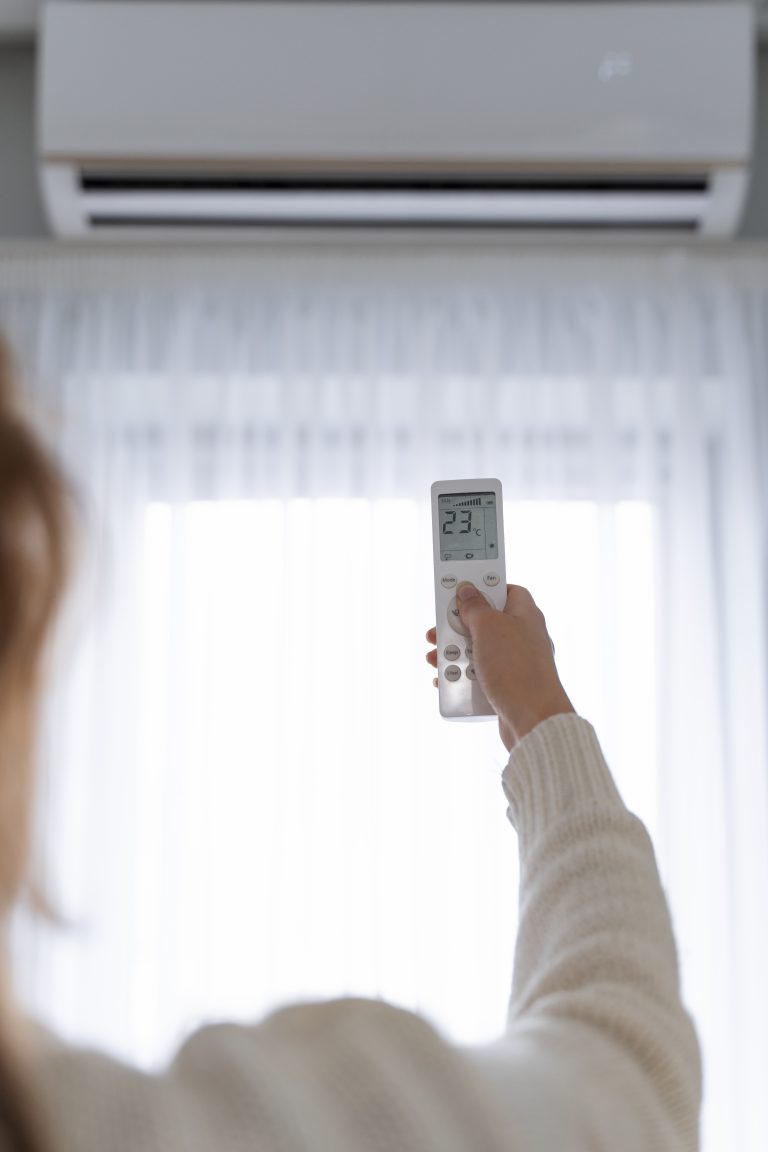 pompe à chaleur interieur femme utilisant une télécommande pour démarrer le chauffage à l'intérieur de la maison