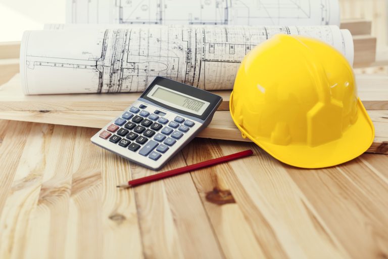 prix geothermie casque jaune avec des plans et une calculatrice sur fond en bois