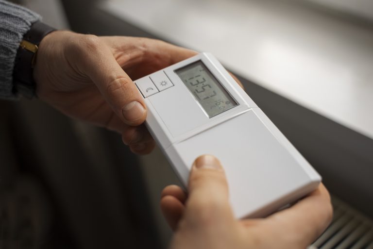température plancher chauffant pompe à chaleur avec un homme ajustant le thermostat chez lui